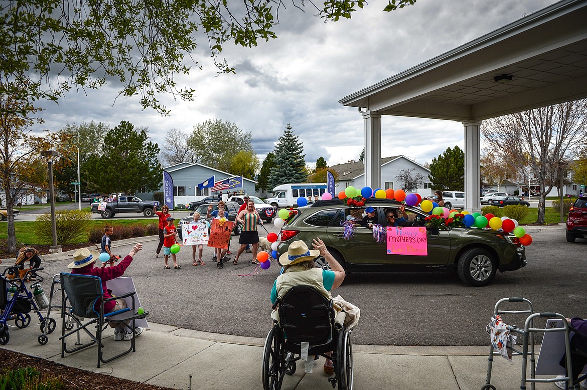 Family members and residents wave during a drive-by parade for Mother's Day at Prestige Assisted Living at Kalispell on Friday, May 8. (Casey Kreider/Daily Inter Lake)