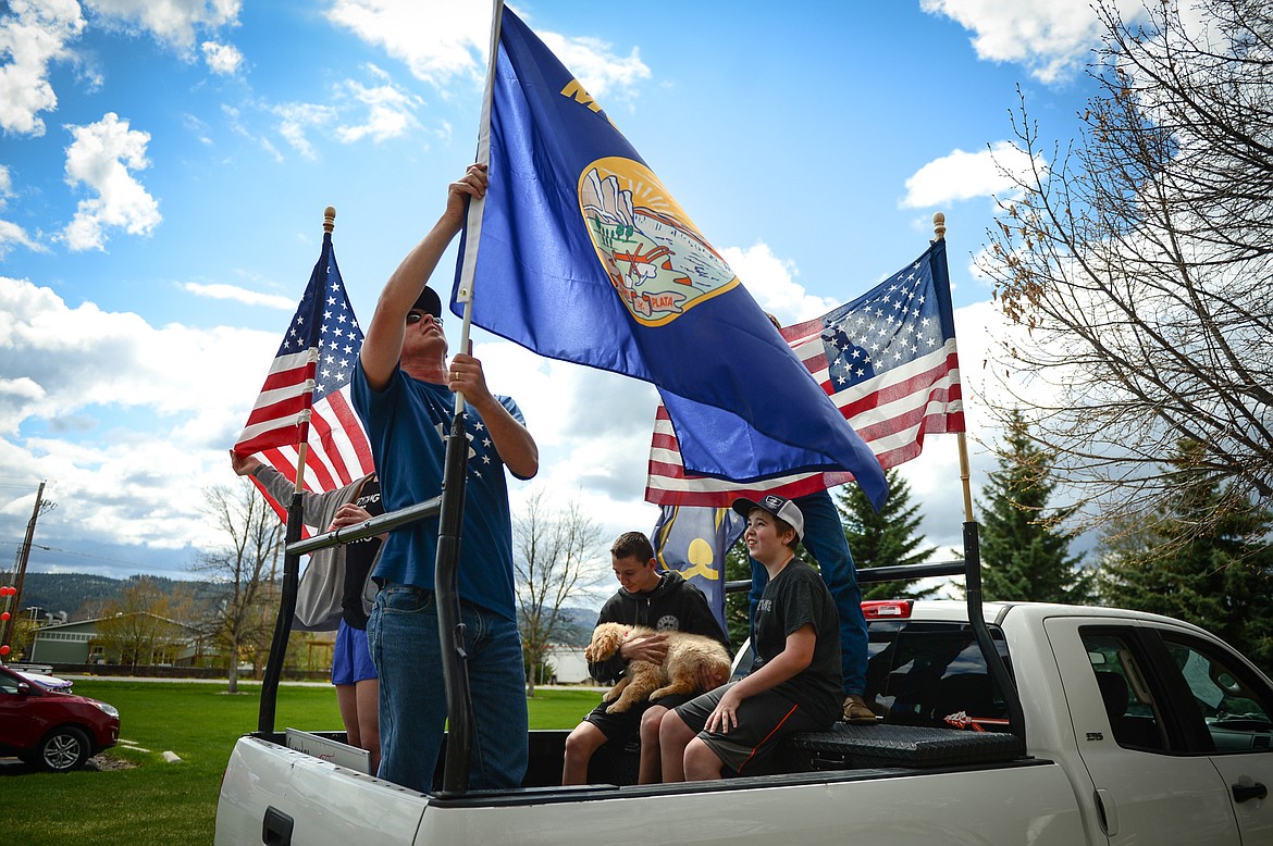 Cody Jones fixes a Montana state flag on the back of his truck as he and family prepare for a drive-by Mother's Day parade to see their grandmother, Jinks Vachal, a resident at Prestige Assisted Living at Kalispell on Friday, May 8. (Casey Kreider/Daily Inter Lake)