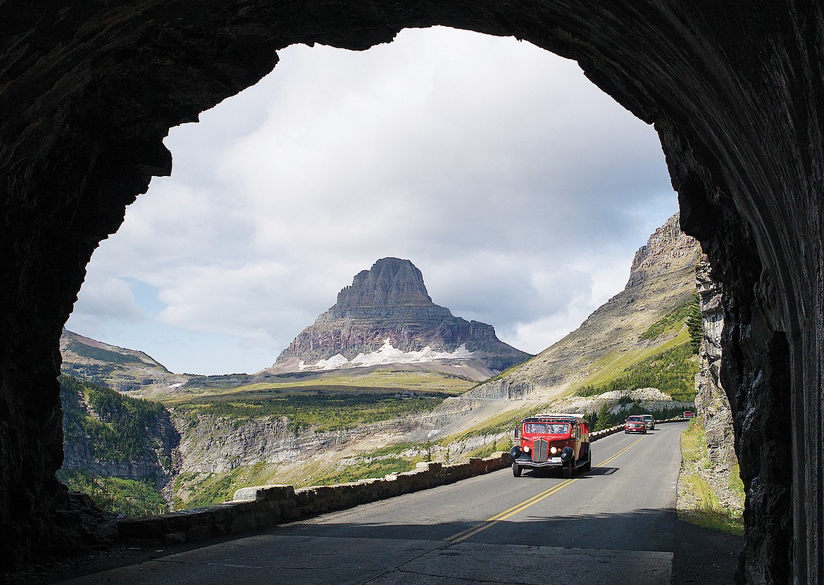 A red bus heads into the East Side Tunnel in Glacier National Park. A deal announced Wednesday would add $1.3 billion a year for deferred maintenance at national parks. (Daily Inter Lake FILE)