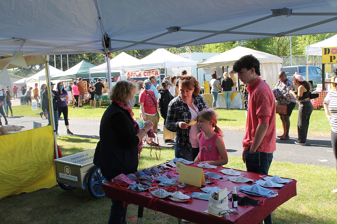 Joel Martin/Columbia Basin Herld 
 Alet Bosse of Sew Dutch helps 7-year-old Alyssa Hersch pick out a mask at the Moses Lake Farmers Market Saturday.