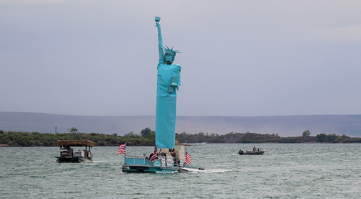 Casey McCarthy/Columbia Basin Herald
Mick Hansen’s Statue of Liberty boat makes its way along the shorelines of Moses Lake on Tuesday as locals gather around the shoreline to investigate the patriotic music ringing through the air.