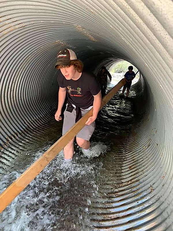 Will Tatum, of Plains, carries a 2x4 through a culvert during the local version of the 2020 Spartan Race. Wlll’s dad, Mike, had the idea after the Spartan Event in Bigfork was cancelled due to the COVID-19 pandemic. (Photo by Mike Tatum)