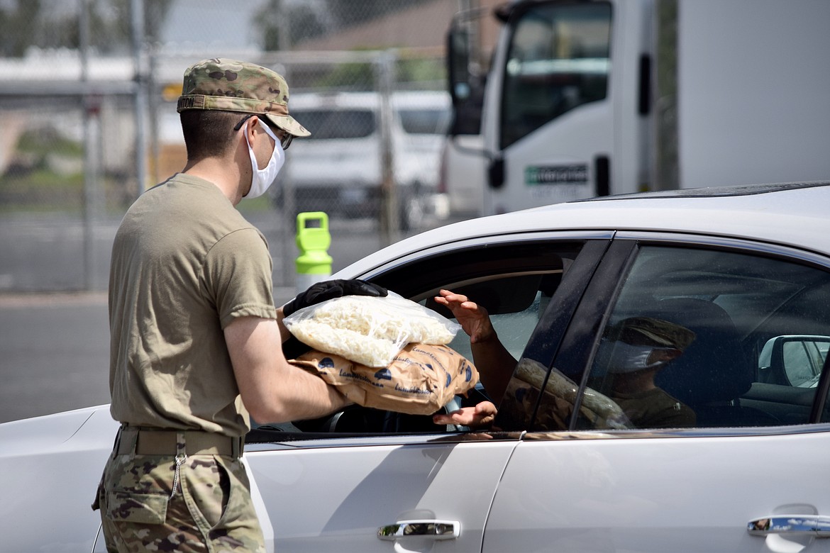 A Washington Army National Guard specialist hands bags of frozen potatoes through car windows on  Tuesday.