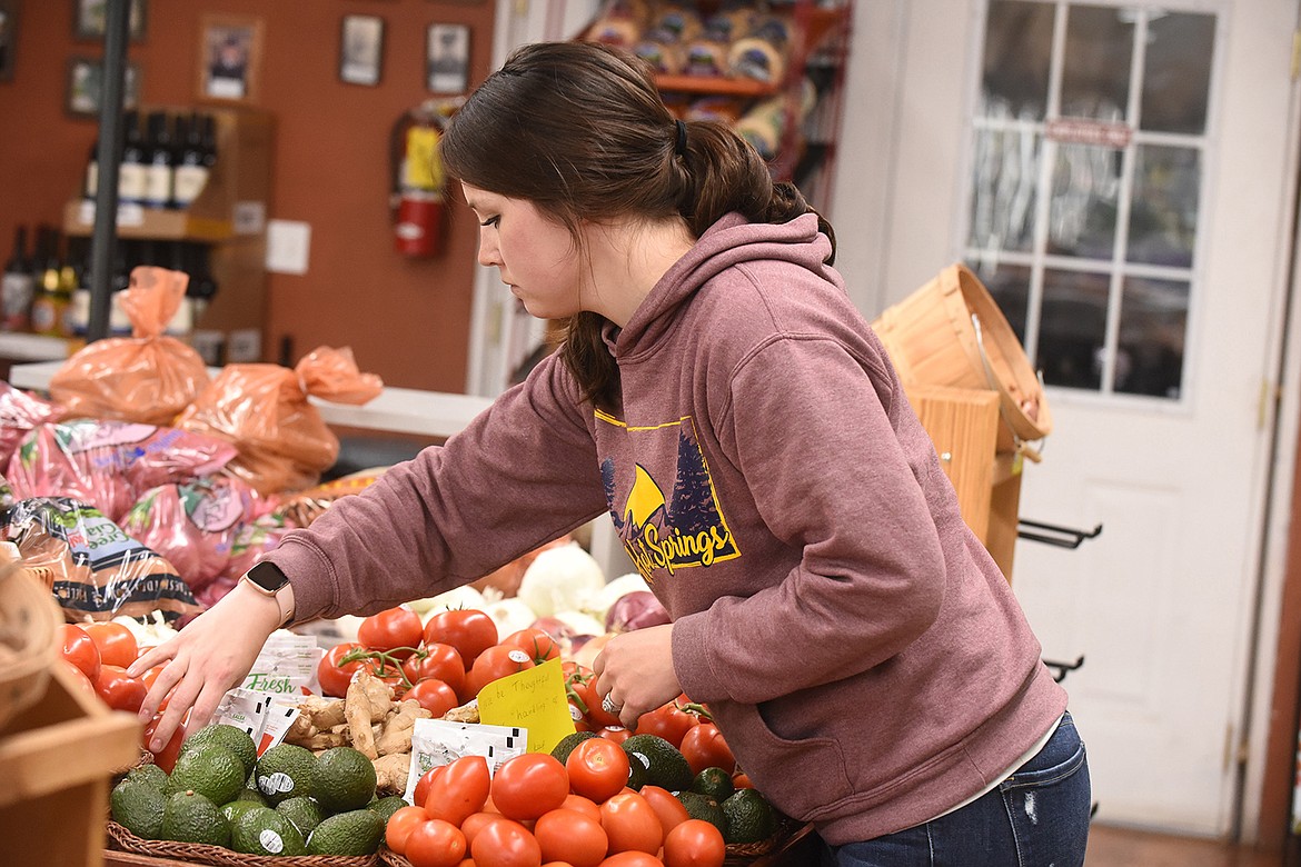 Randi Arnold arranges vegetables at Buck’s Grocery in Hot Springs. The daughter of owners Jim and Paula Stobie, Arnold spends three days a week at the store, helping run it with manager Dalyn Frazier. (Scott Shindledecker/Valley Press)