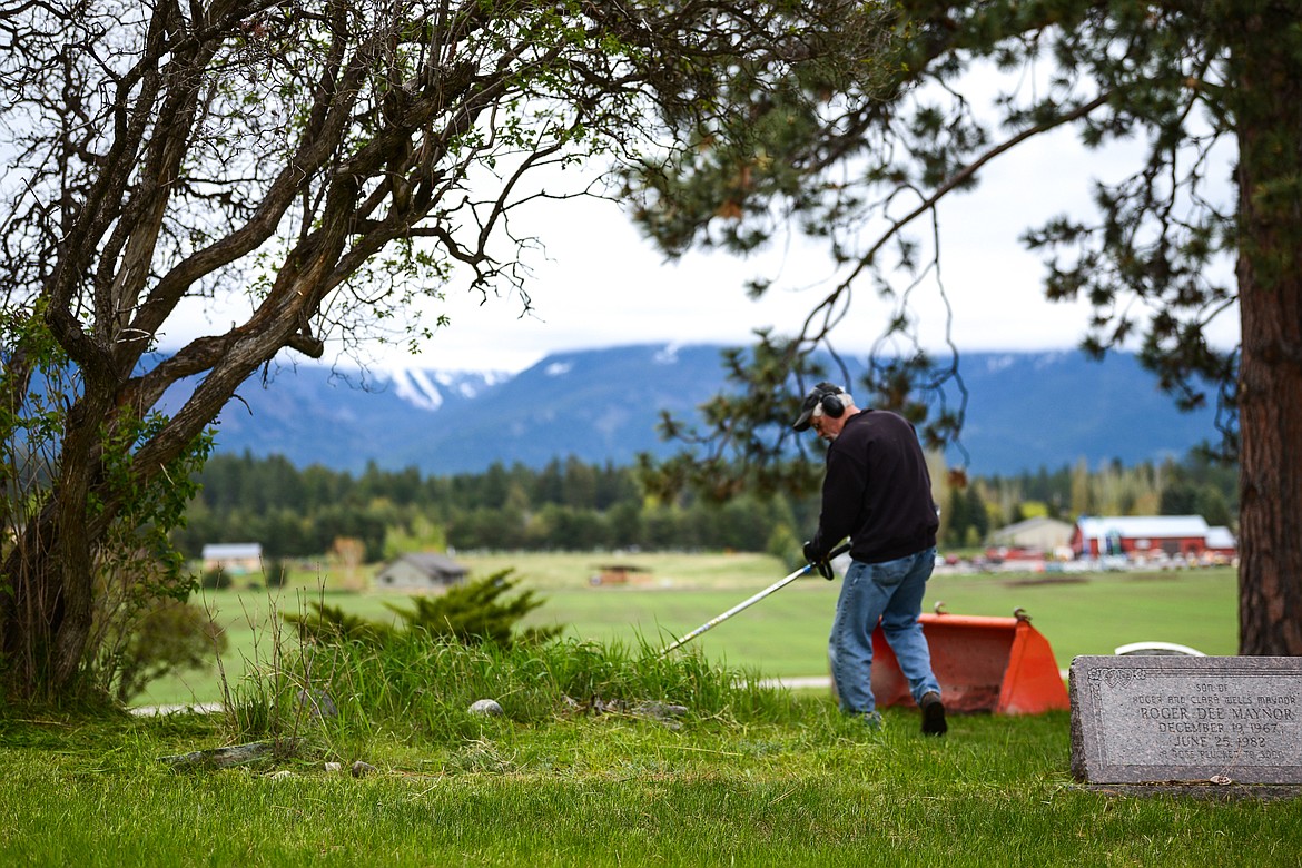 Tom Maxwell uses a weedwacker around a group of gravestones during the annual cleanup at Lone Pine Cemetery in Bigfork on Friday, May 15. (Casey Kreider/Daily Inter Lake)