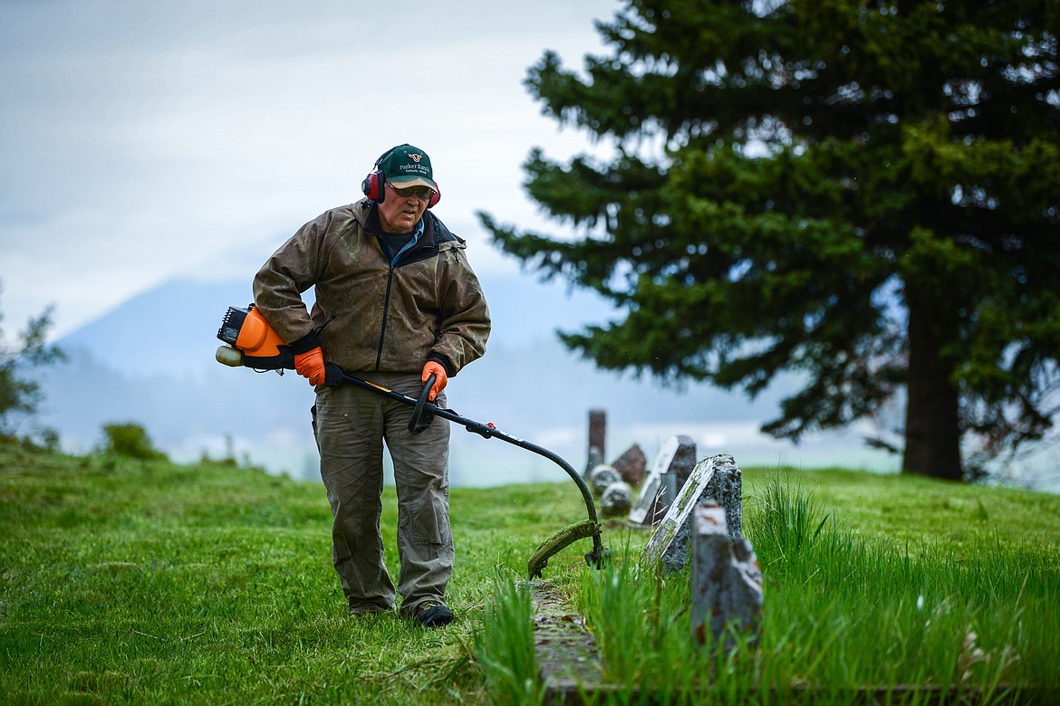 Bill Morton uses a weedwacker around a group of gravestones during the annual cleanup at Lone Pine Cemetery in Bigfork on Friday, May 15. (Casey Kreider/Daily Inter Lake)