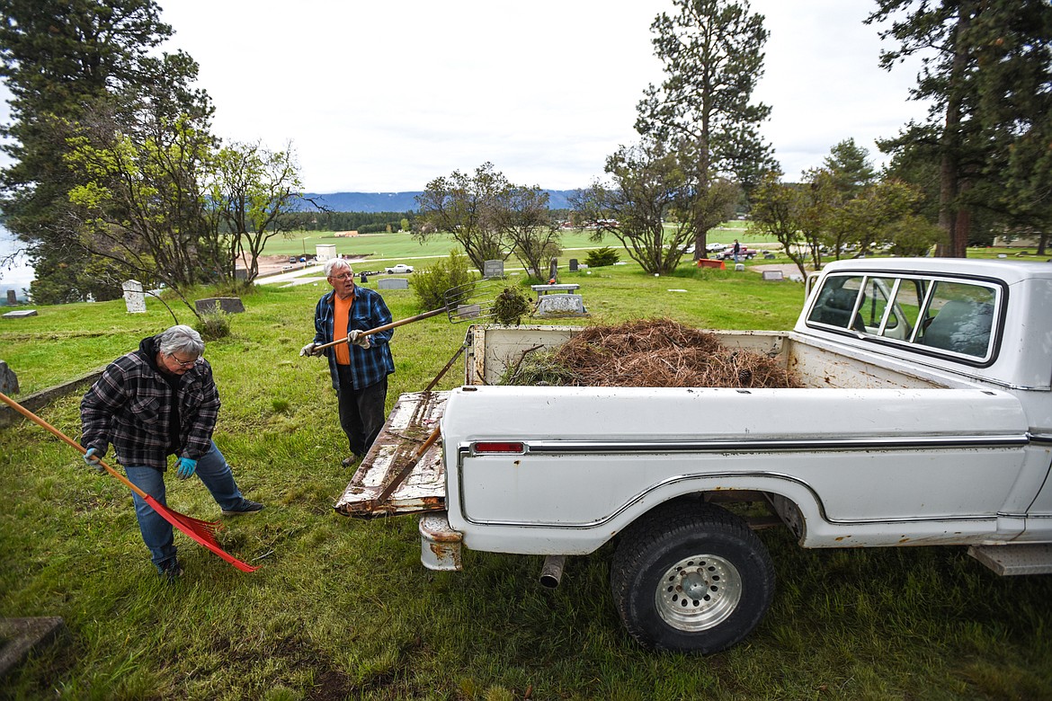 Jessie and Jeff Wade scoop debris into the back of a pickup to be transported to a burn pile during the annual cleanup at Lone Pine Cemetery in Bigfork on Friday, May 15. (Casey Kreider/Daily Inter Lake)