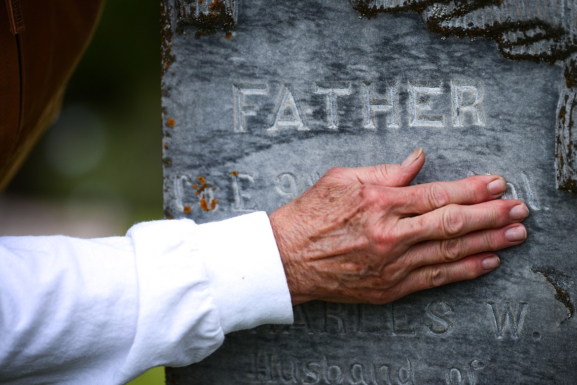 Arlene Wilson cleans debris off the lettering of a gravestone belonging to Charles W. Morrill, a U.S. Army veteran of the Civil War, at Lone Pine Cemetery in Bigfork on Friday, May 15. (Casey Kreider/Daily Inter Lake)