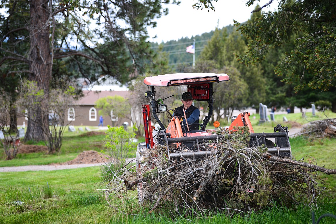 Tim Darr scoops up piles of debris during the annual cleanup at Lone Pine Cemetery in Bigfork on Friday, May 15. (Casey Kreider/Daily Inter Lake)