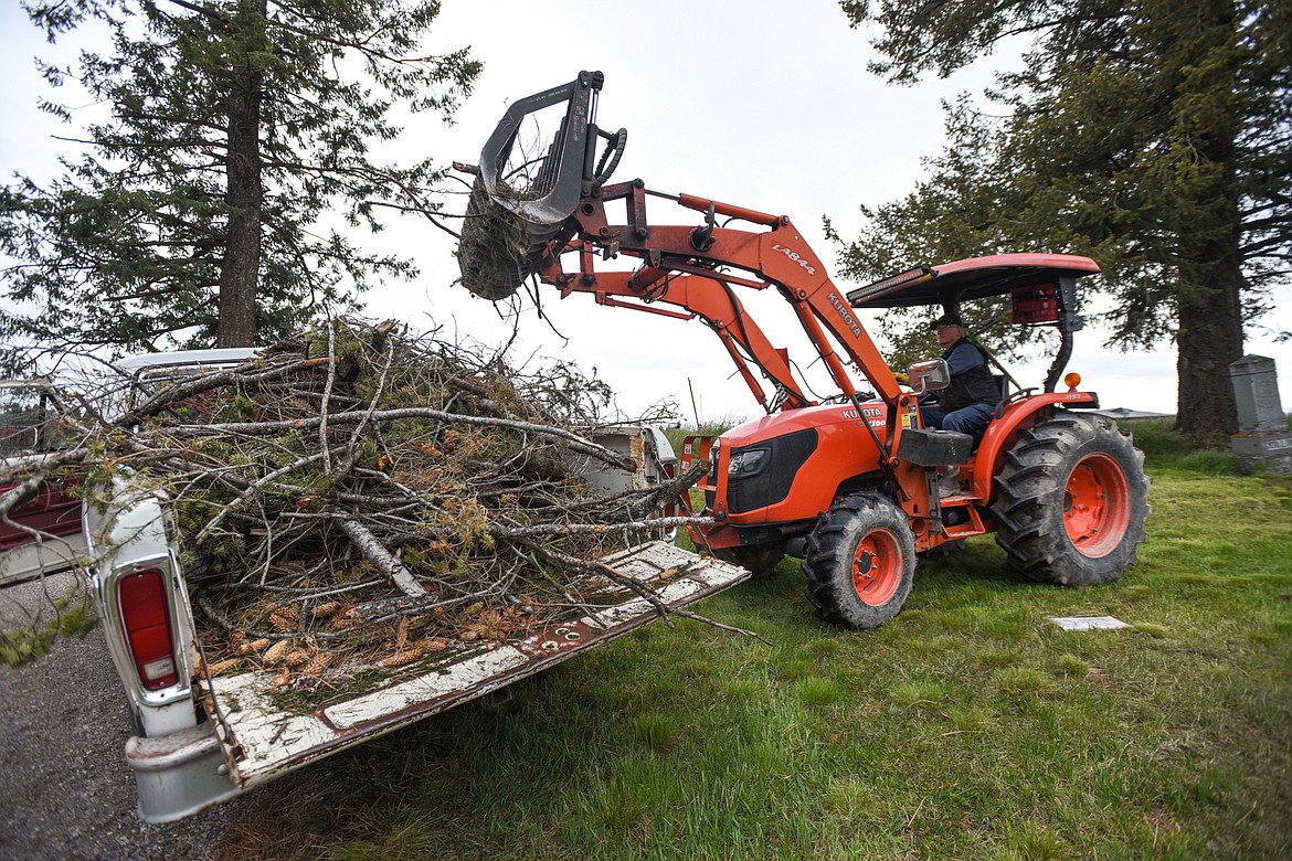 Tim Darr scoops up piles of debris during the annual cleanup at Lone Pine Cemetery in Bigfork on Friday, May 15. (Casey Kreider/Daily Inter Lake)