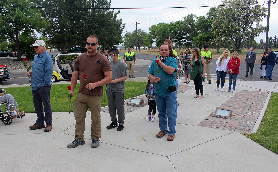 Casey McCarthy/Columbia Basin Herald 
  
 Participants line up to leave a rose in remembrance of 87 military service members killed in a 1952 plane crash at Larson Air Force Base during a remembrance ceremony Monday in Moses Lake.