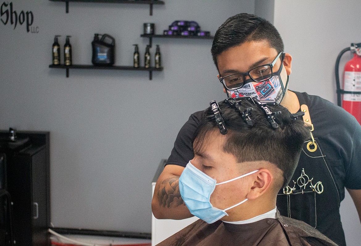 Slik Cutzz barber Angel Tapia trims client Gustavo Guzman’s hair on Tuesday on the shop’s first day open since business closures went into effect in March.