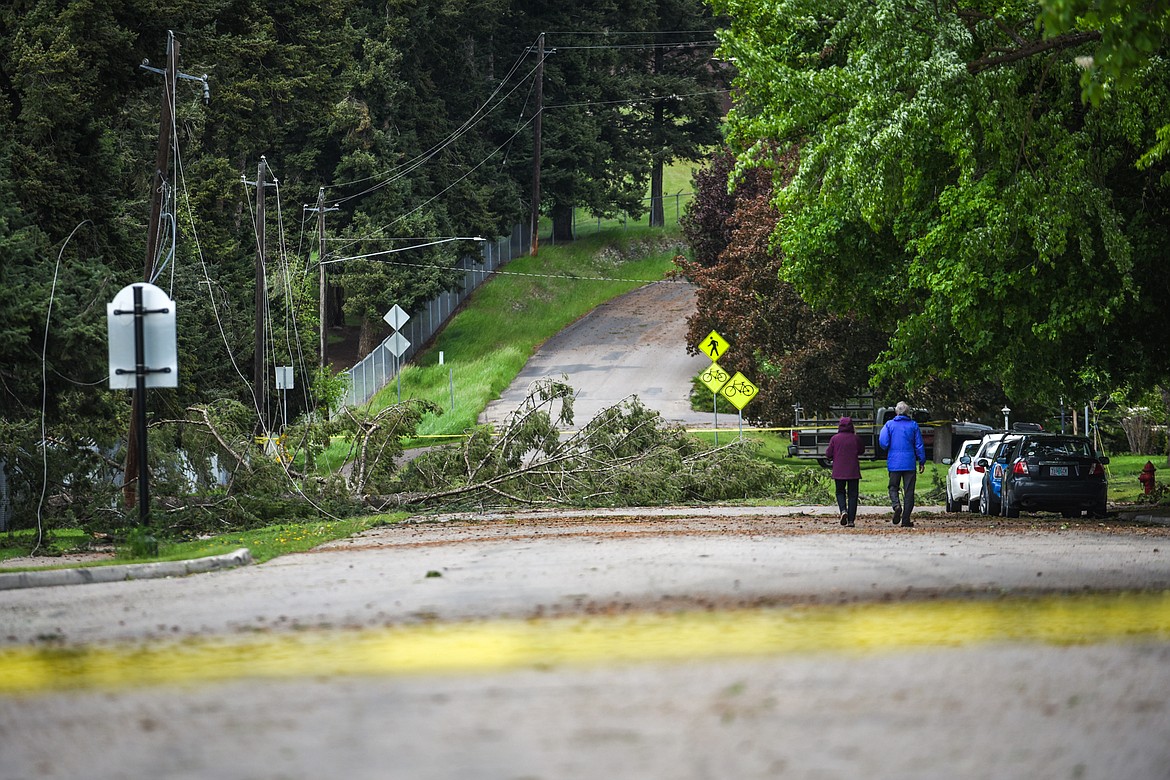 A couple walks down North Main Street near Lawrence Park where several trees fell across power lines during an early-morning storm that left thousands in the valley without power on Sunday, May 31. (Casey Kreider/Daily Inter Lake)