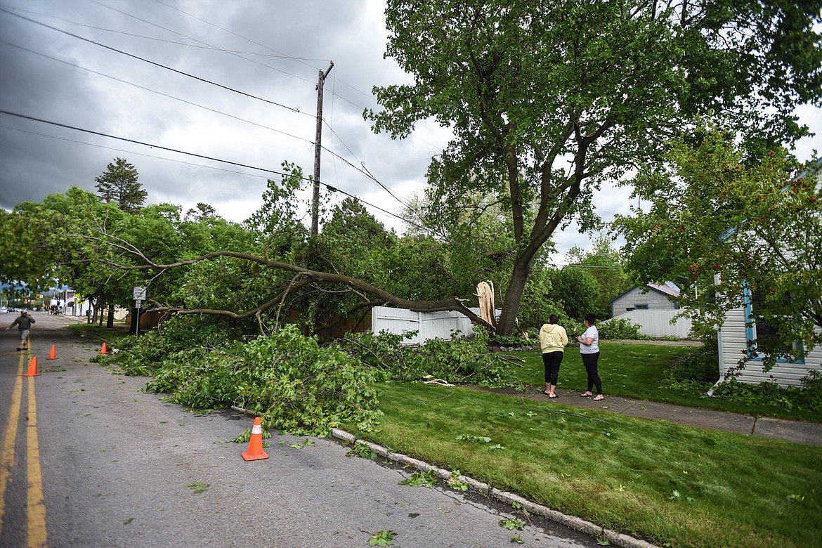 Natasha George and Danae Maxwell take photos of storm damage to a neighboring property along Fourth Street West near Elrod Elementary in Kalispell on Sunday, May 31. (Casey Kreider/Daily Inter Lake)