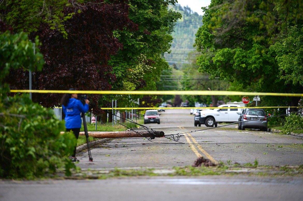 A television journalist records video of storm damage along Fourth Street West near Elrod Elementary in Kalispell on Sunday, May 31. (Casey Kreider/Daily Inter Lake)