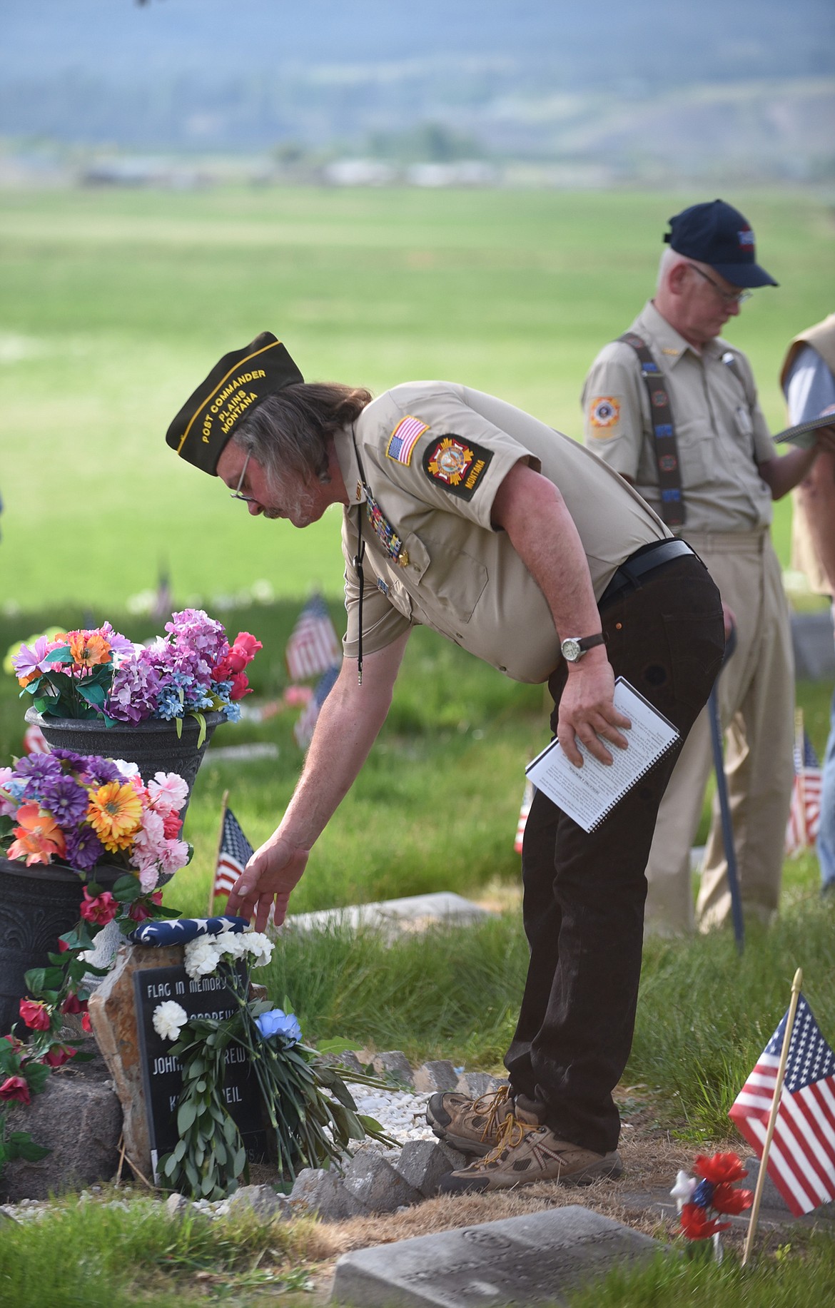 PLAINS VFW member Ron Kilbury places an American flag at a memorial at the Plains Cemetery last Saturday during the group’s annual remembrance of those who died while serving in the United States Armed Forces. (Scott Shindledecker/Valley Press)