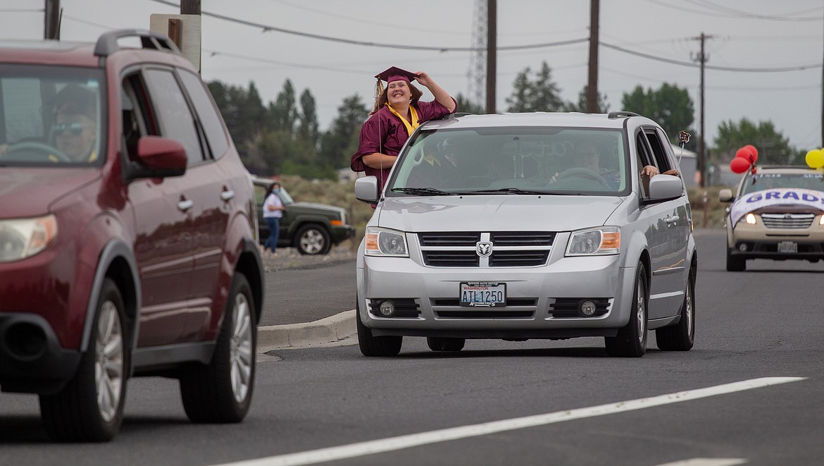 Casey McCarthy/Columbia Basin Herald 
 A Moses Lake graduate leans out of a van as cars leave Grant County Fairgrounds.
