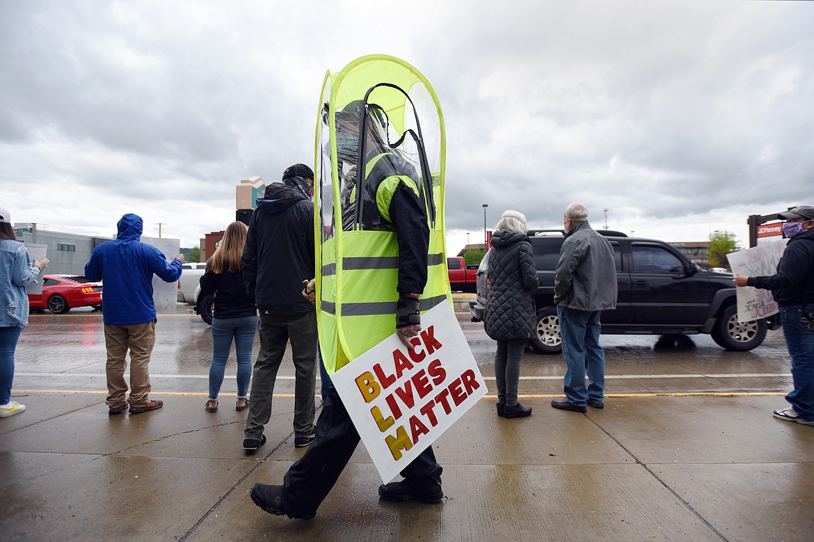 A protester wears a protective suit and holds a sign during a protest at Depot Park denouncing police violence against people of color in Kalispell on Saturday, June 6. (Casey Kreider/Daily Inter Lake)