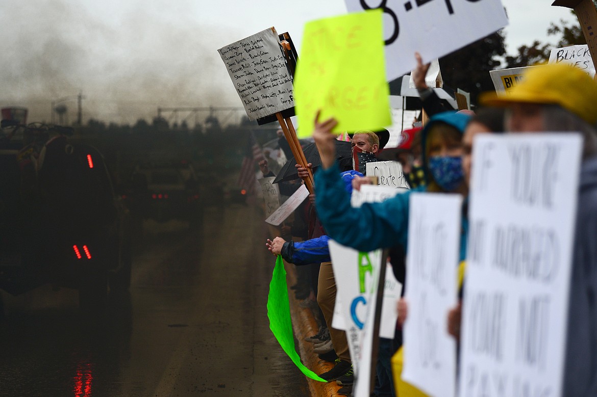 Drivers in pickup trucks “roll coal” as they drive past a group of protesters along North Main Street at Depot Park during a protest denouncing police violence against people of color in Kalispell on Saturday, June 6. (Casey Kreider/Daily Inter Lake)