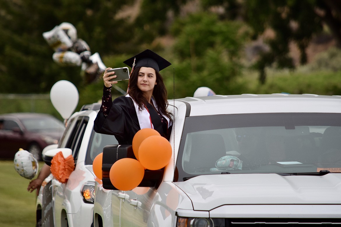 Charles H. Featherstone/Columbia Basin Herald 
 Ephrata High Schjool senior Shayla Whalen takes a panoramic picture of the EHS drive-in graduation service on Friday.