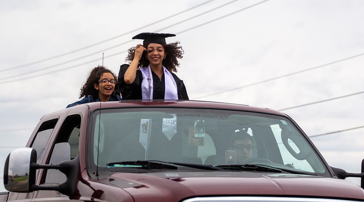 A RHS graduate hangs on to her cap as she heads down the road during the graduation parade on Friday night.