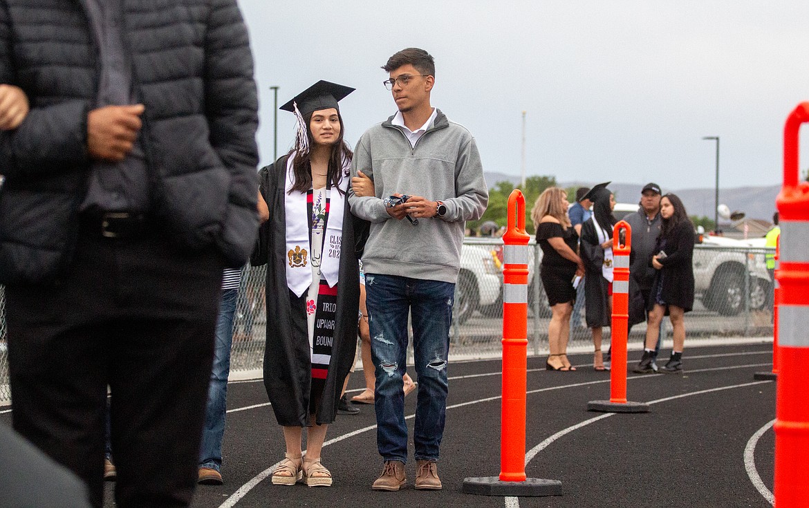 Graduates and their families, separated as groups, wait to make their way across the graduation stage at David Nielsen Memorial Field on Friday night in Royal City.