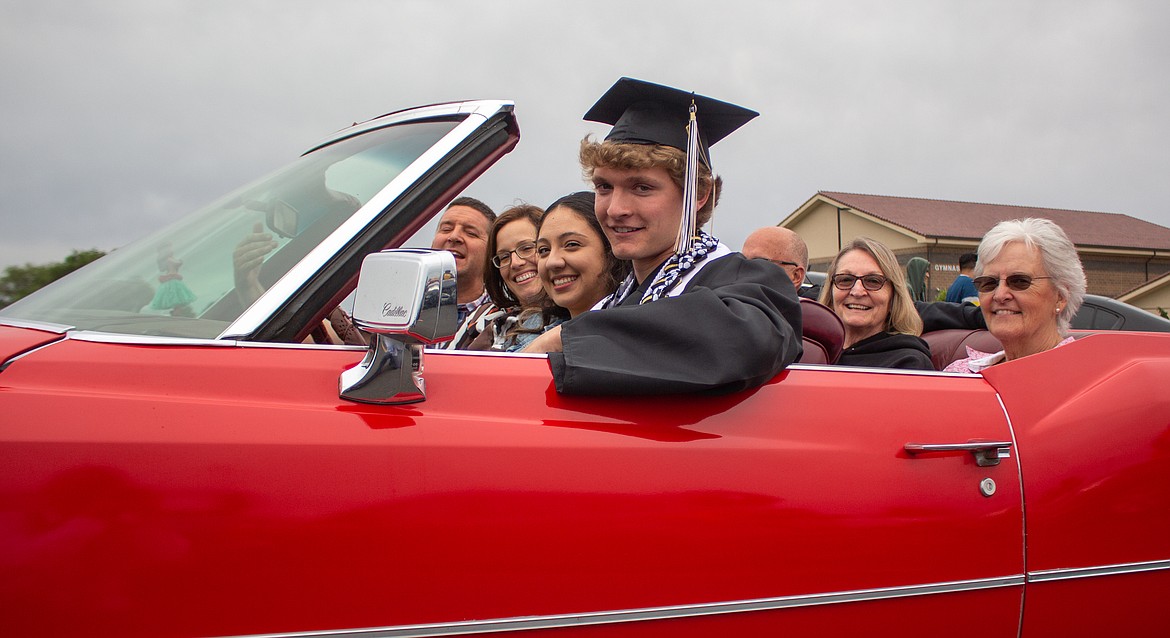 An RHS graduate smiles with his family for a photo as he makes his way into the parking lot before ceremonies begin on Friday night in Royal City.