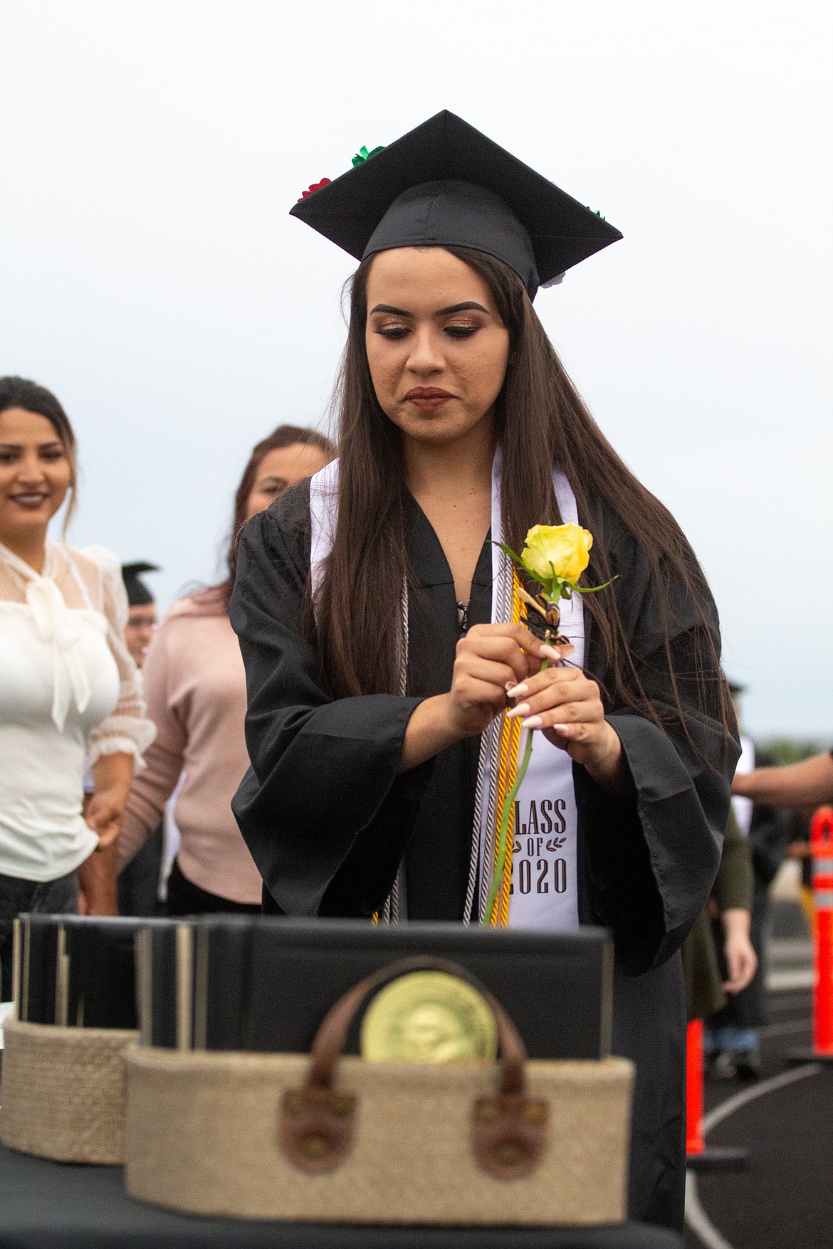A Royal High School graduate grabs her rose and diploma cover before making her way to the stage on the track at David Nielsen Memorial Field on Friday evening.
