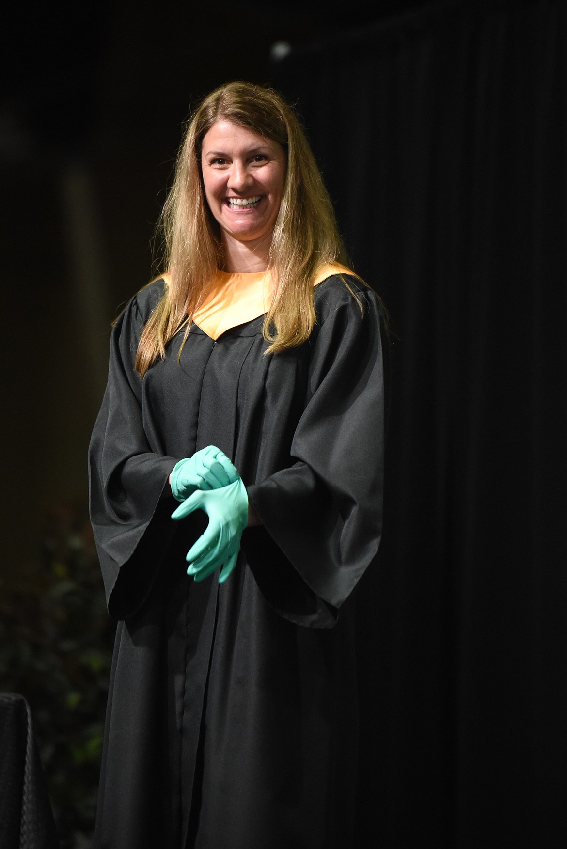 Whitefish School Board Chair Katie Clarke smiles as she dons gloves before handing out diplomas during Saturday's Whitefish High School Graduation. (Daniel McKay/Whitefish Pilot)