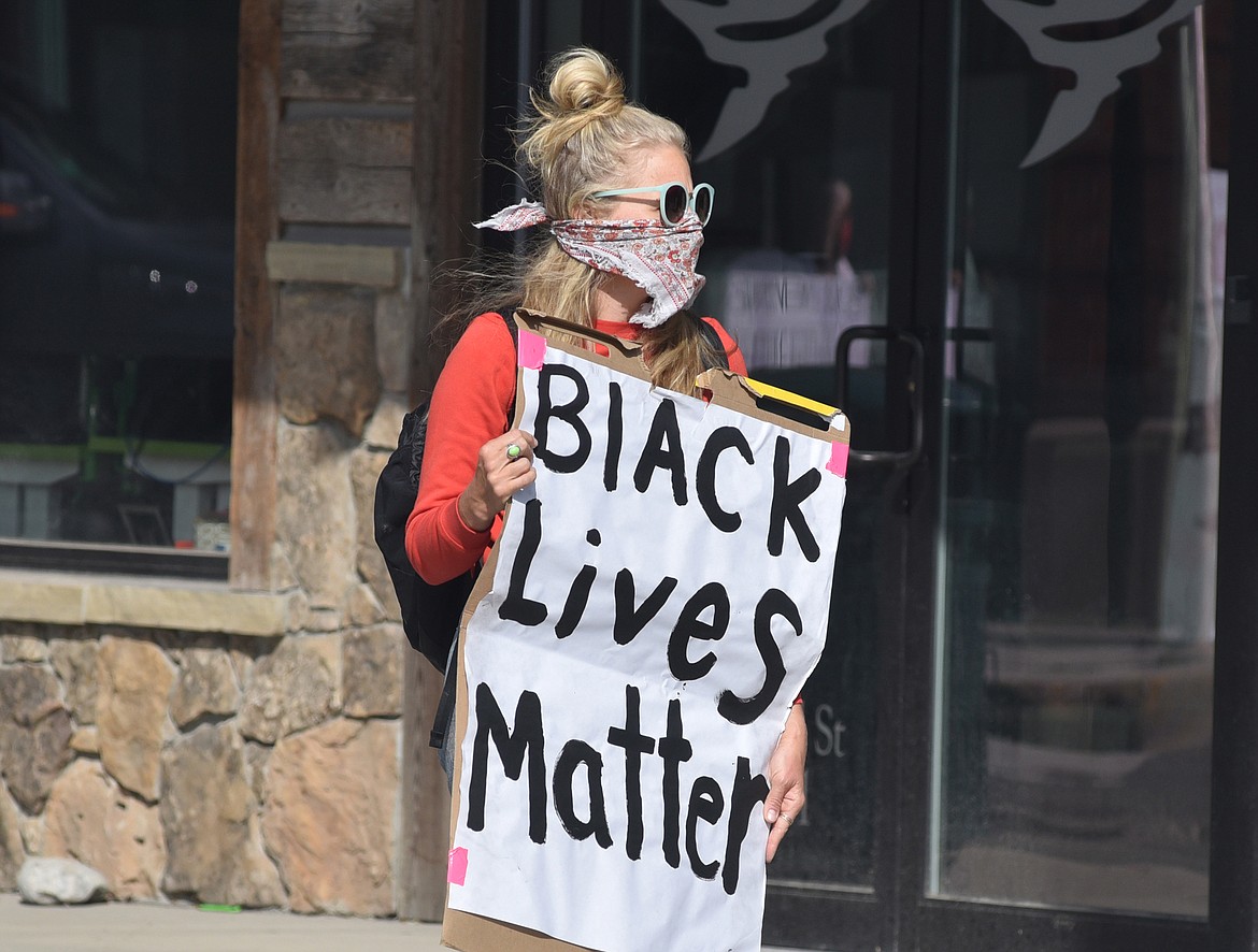 Allison Williams holds up a Black Lives Matter sign on Wednesday evening in downtown Whitefish while standing amongst a group of people gathered to protest the recent death of George Floyd and show support for the Black Lives Matter movement. (Heidi Desch/Whitefish Pilot)