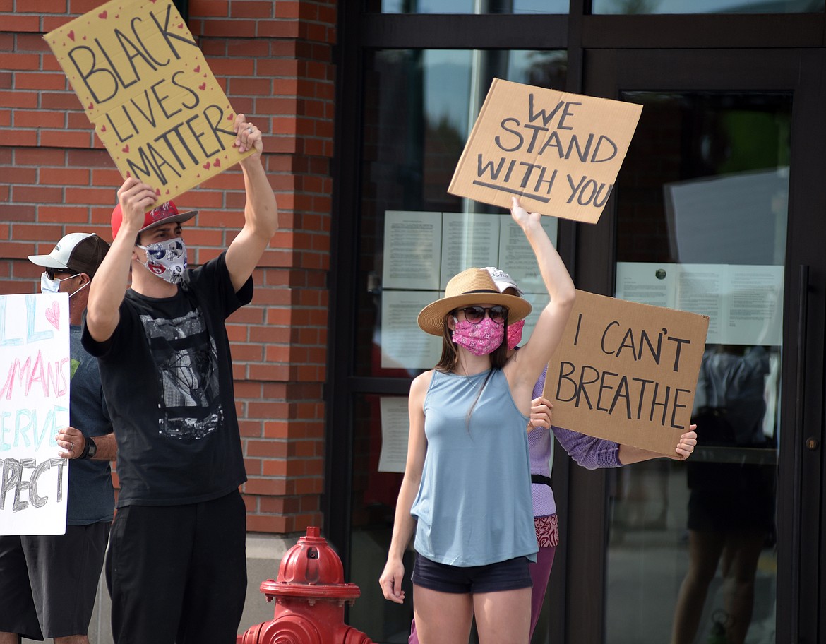 Anthony Correa and Carley Joe Correa stand holding signs in front of a group of protestors outside Whitefish City Hall Wednesday evening. Demonstrators were gathered protesting the death of George Floyd and showing support for the Black Lives Matter movement. (Heidi Desch/Whitefish Pilot