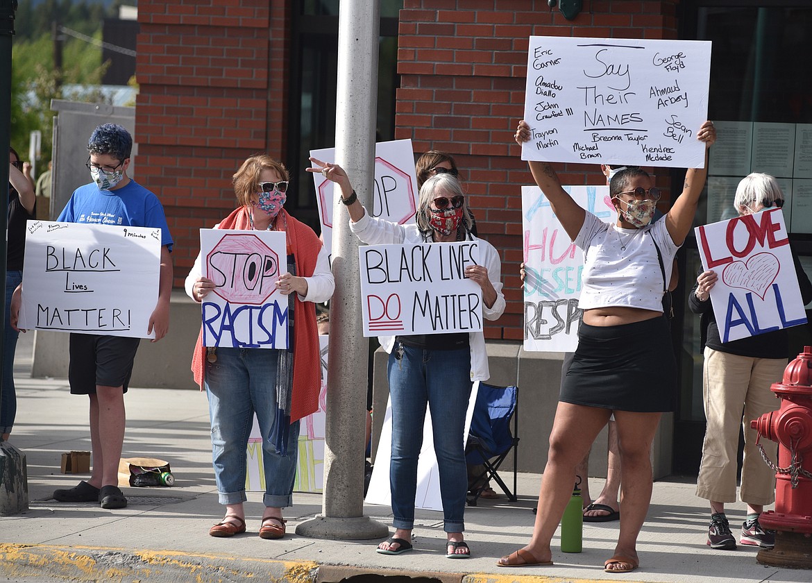 Demonstrators hold up signs in front of Whitefish City Hall downtown Wednesday evening protesting the recent death of George Floyd and showing support for the Black Lives Matter movement. (Heidi Desch/Whitefish Pilot)