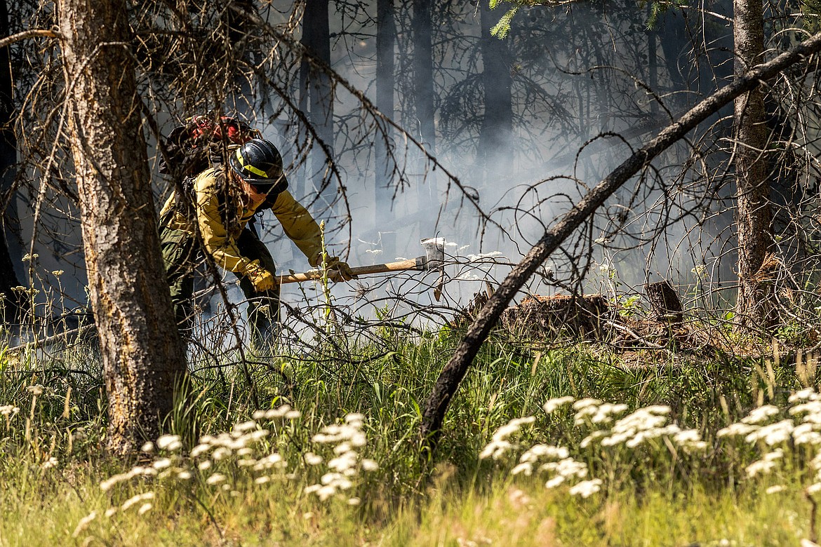 A U.S. Forest Service firefighter helps fight a grass and timber fire along Luscher Drive Wednesday. The fire was a "hold over" from a slash pile that was burned in May, said Libby Volunteer Fire Department Chief Tom Wood. (John Blodgett/The Western News)