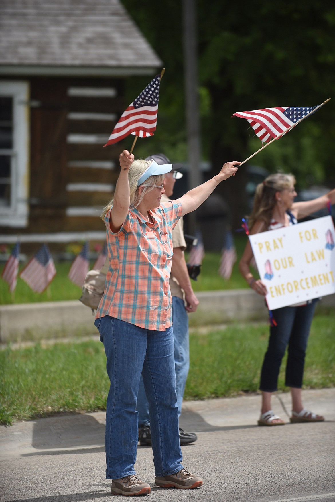 Plains resident Sally Lilja waves to U.S. flags Friday afternoon on Montana 200 during a rally to support law enforcement officers. (Scott Shindledecker/Valley Press)