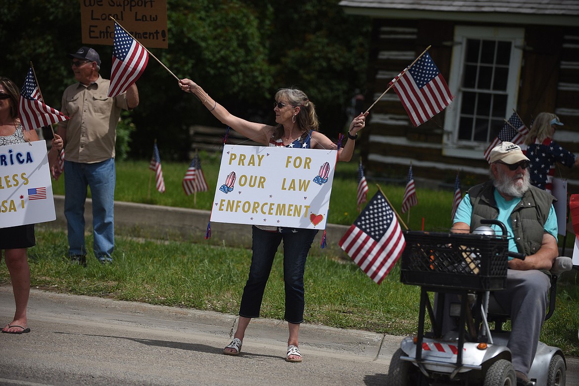 Sanders County resident Shelly Rummel waves a pair of U.S. flags and displays a sign showing support for law officers Friday afternoon in Plains during a rally. (Scott Shindledecker/Valley Press)