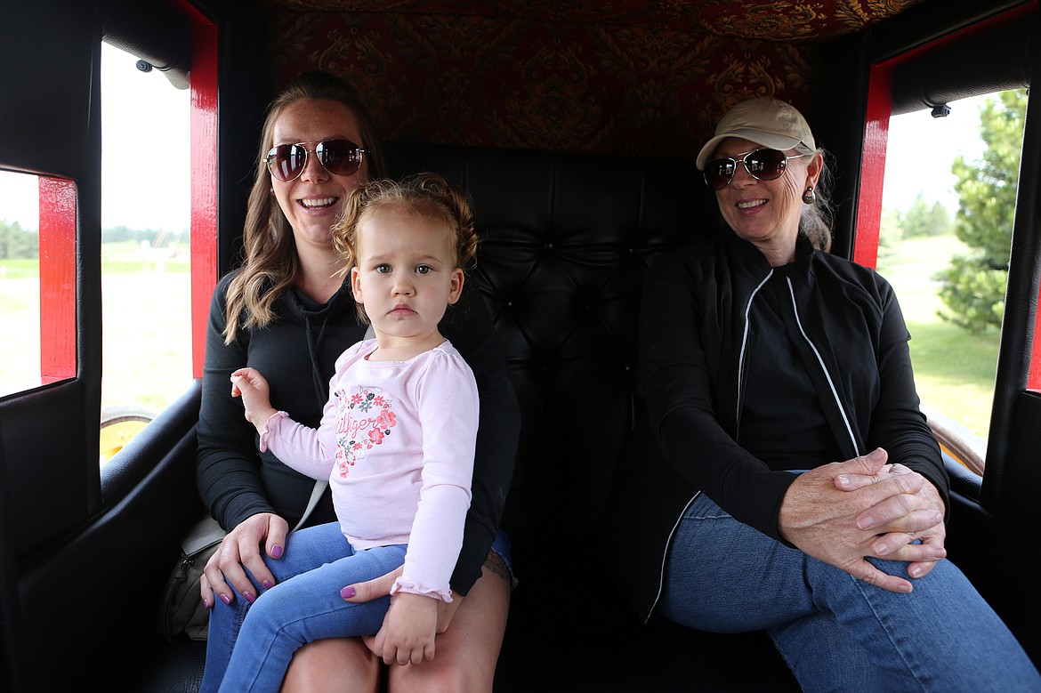 $ID/NormalParagraphStyle:Chardee Timis, Brylee Wildes, 2,  and Cathy Osborn ride inside Gene Bushnell’s stagecoach Friday morning, June 12.