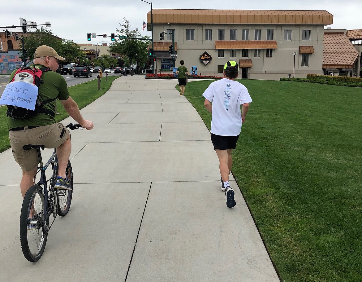 Jim Kinnard, a Special Olympian from Lake City High School, runs in front of The Coeur d’Alene Resort on Saturday as part of a “virtual” Missoula half-marathon. The actual race, scheduled for June 28, was canceled due to the COVID-19 pandemic. At left is Kinnard’s dad, Jeff, serving as race support. Running ahead is Carter Gordon, a recent Lake City grad who will attend Lewis-Clark State College and compete in cross country and track and field. Gordon is one of Kinnard’s community support workers, and they often train together. They ran the Missoula half-marathon and Coeur d’Alene half-marathon together last summer. On Saturday, Gordon ran the 13.1 miles in 1 hour, 40 minutes, pacing Kinnard and cheering him on to the finish. Kinnard finished in 2:02. Kinnard is also training with ParaSports Spokane in hopes of qualifying for the USA Paralympics in the future.