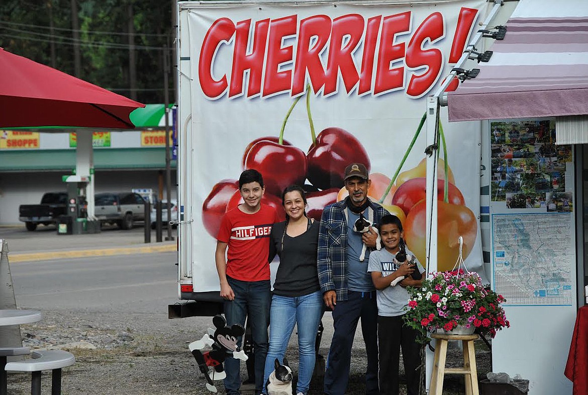 Victor Lopez stands out front of his "summer home" at his family's cherry stand near the four way stop in St. Regis with his daughter Vanessa, son Adrian and nephew Oscar. (Amy Quinlivan/Mineral Independent)