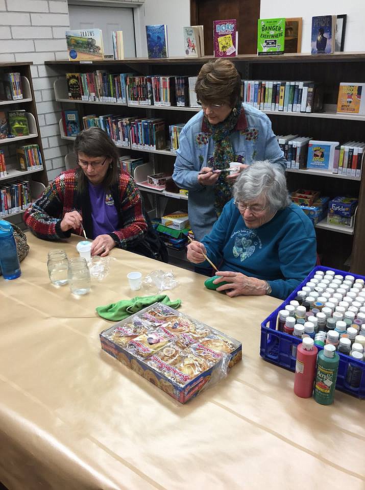 Sam Miller, center, watches as some students try their hands at rock painting during a class in the Soap Lake Public Library.