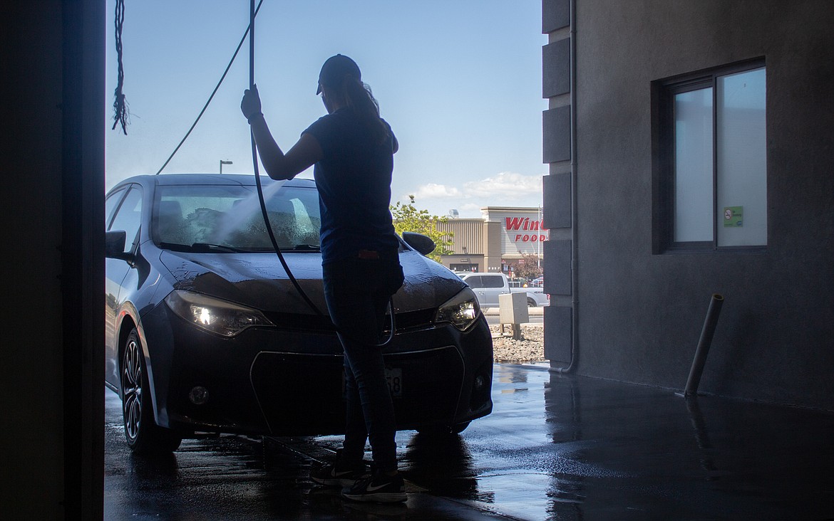 Casey McCarthy/Columbia Basin Herald 
 Jasmine Erdmann of Sun Splash Car Wash in Moses Lake hoses down the front end of a car before it heads into the wash on Tuesday afternoon.
