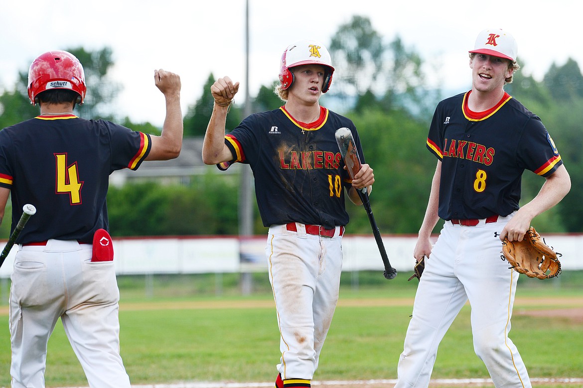 Kalispell Lakers AA's Connor Drish, center, is congratulated by teammates Kobe Burland, left, and Jack Corriveau after scoring on a fielder's choice by Danny Kernan in the second inning against the Billings Scarlets at Griffin Field on Tuesday. (Casey Kreider/Daily Inter Lake)