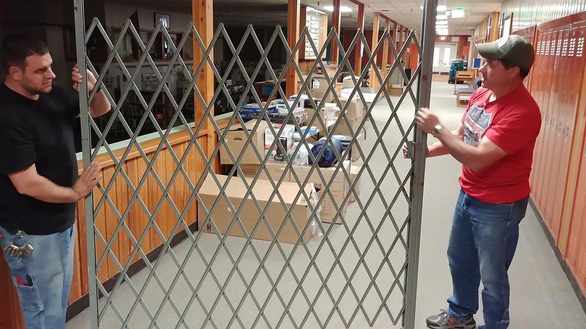 Plains School Superintendent Tom Chisholm, right, and maintenance worker Matthew Hitchcock hold onto a 90-year old steel gate from the original high school gym that will be installed in the new building. (Chuck Bandel/Valley Press)