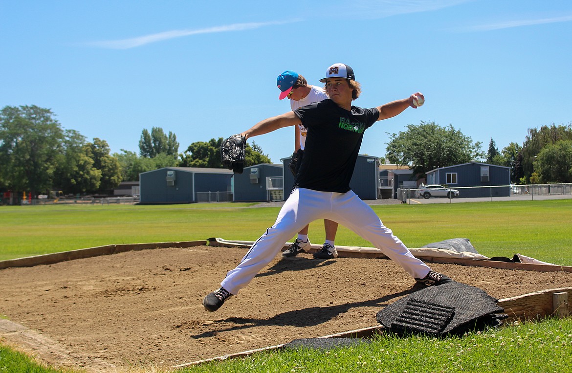 Asher Lindgren, front, fires a pitch during the Columbia Basin Riverdogs practice on Wednesday afternoon in Ephrata, with his brother, Dax Lindgren, getting set for another throw behind him.