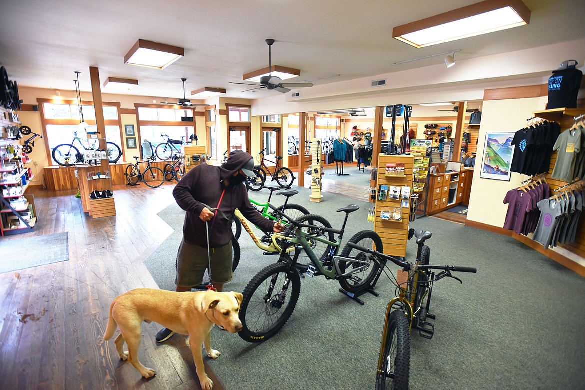 Josh Phillips, of Asheville, North Carolina, checks out a Santa Cruz full suspension bike with his dog Captain at Glacier Cyclery & Nordic in Whitefish on Friday, July 10. (Casey Kreider/Daily Inter Lake)