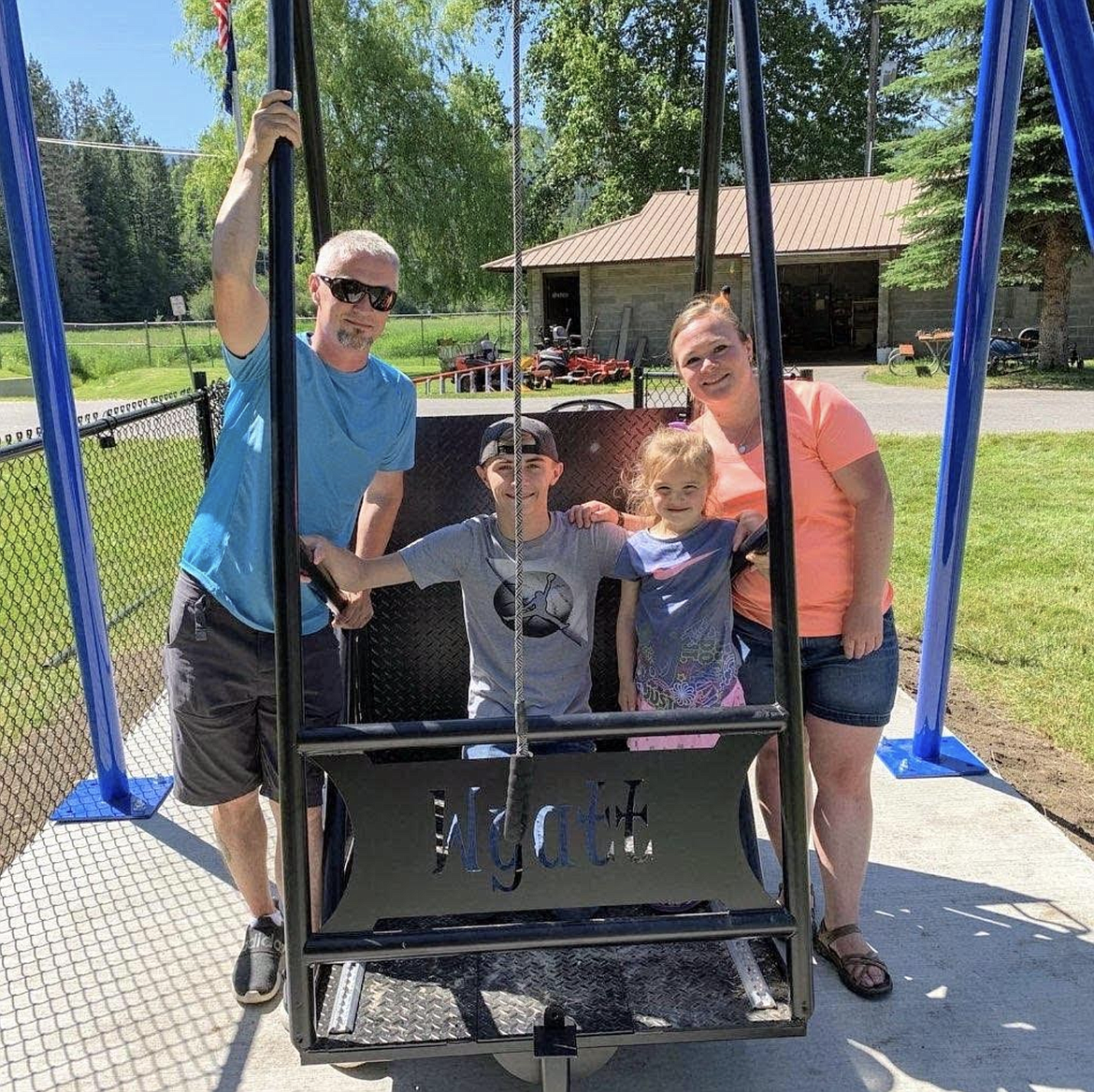 From left: Wayne Blalack, Wyatt’s father; Coleman Blalack, brother; Sadie Blalack, sister; and Stephanie Blalack, mother, pose with the new fully-functional wheelchair accessible swing at the West Shoshone Park in Pinehurst.