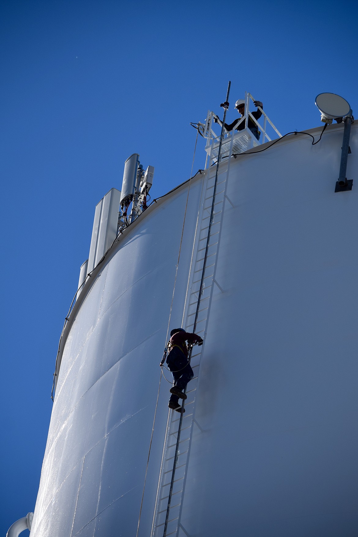 Workers from HCI Industrial & Marine Coating climb down off the Kittleson Road water tower in Moses Lake after painting it.