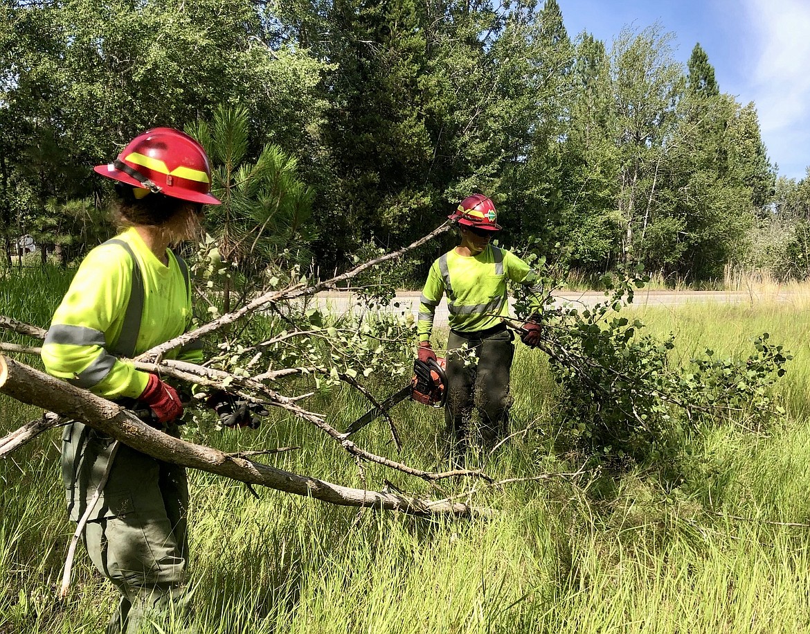 Idaho Department of Lands wildland firefighters Jaron Figueroa and Tayler Bush work to clear up wood debris and other possible fuels from the side of Interstate 90 on Wednesday. This work not only helps prevent fires from starting near I-90, but it also helps ITD with everyday roadside management.