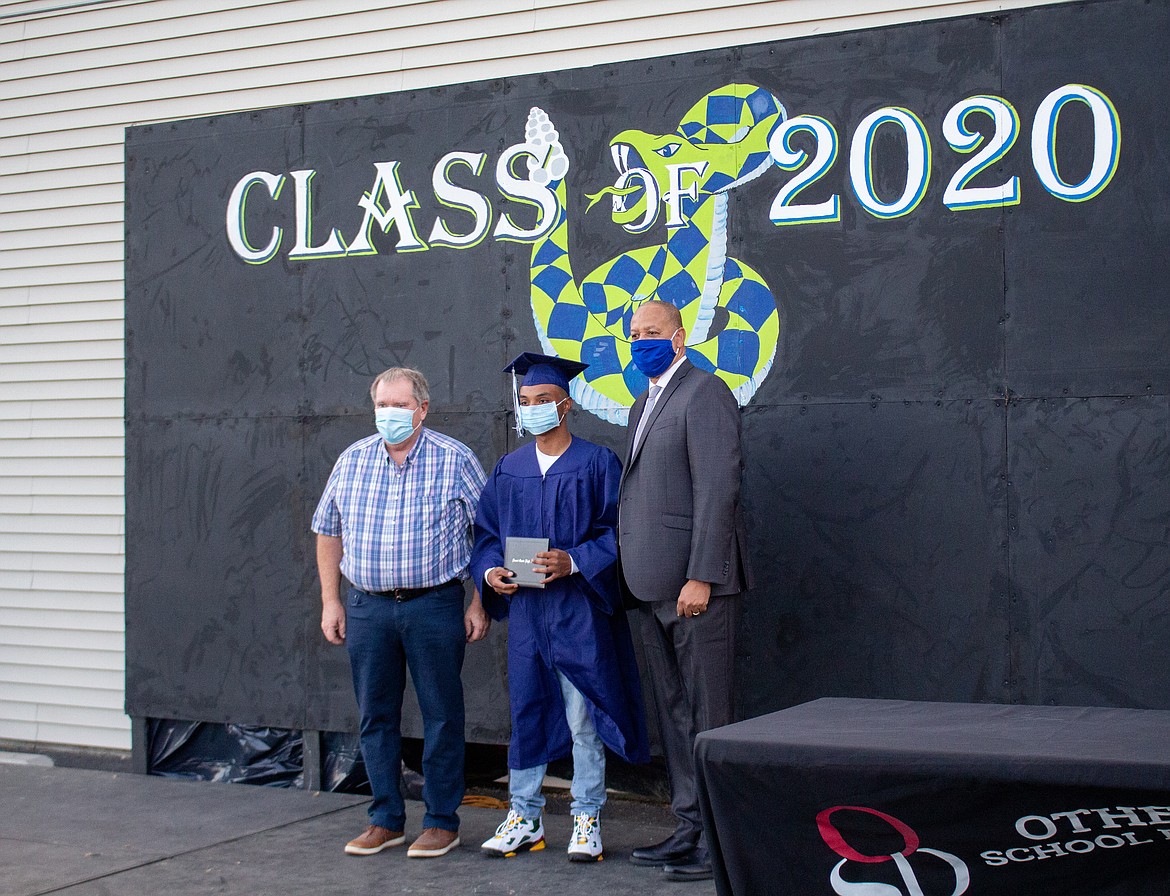 Casey McCarthy/The Sun Tribune 
 Othello School Board member Ken Johnson, Desert Oasis graduate Kevin Rafalian, and Othello School District Superintendent Dr. Kenneth Hurst pose for a photo together on stage as Rafalian is honored alongside his fellow 2020 Desert Oasis High School graduates last Thursday evening.