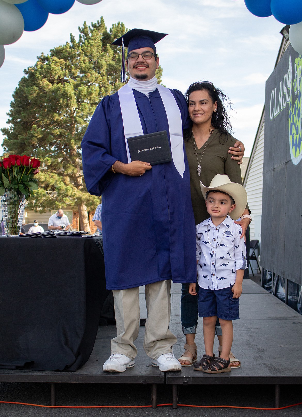 Casey McCarthy/The Sun Tribune 
 2020 Desert Oasis graduate Eduardo Garcia poses with family members for a photo on stage after receiving his diploma cover on Thursday, July 16.