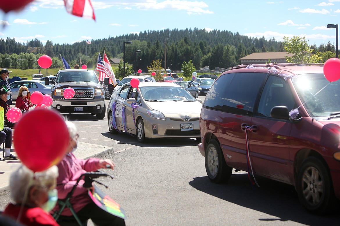 $ID/NormalParagraphStyle:Two dozen cars cruise by Rising Mountains Assisted Living to celebrate resident Harriet Dent’s 100th birthday.